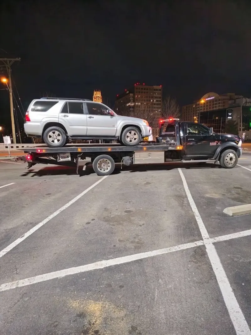 Downtown Nashville towing — Hook Em' Up Towing flatbed loading an SUV off Broadway near The Gulch