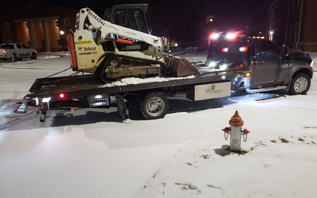 Equipment transport near me Nashville TN - bobcat skid steer being loaded onto professional flatbed trailer