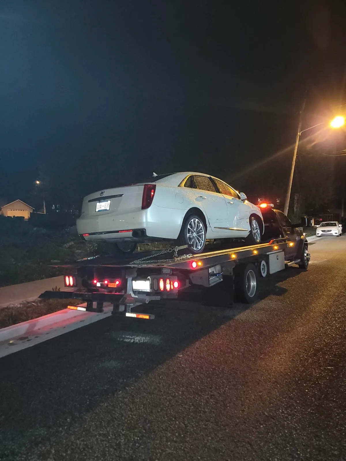 Hook Em' Up Towing flatbed loading a wrecked vehicle at a Nashville accident scene at night