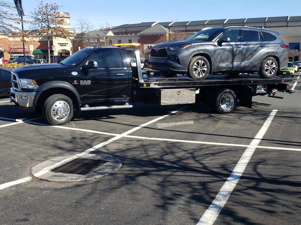 Black flatbed tow truck transporting Toyota Highlander SUV safely in Nashville