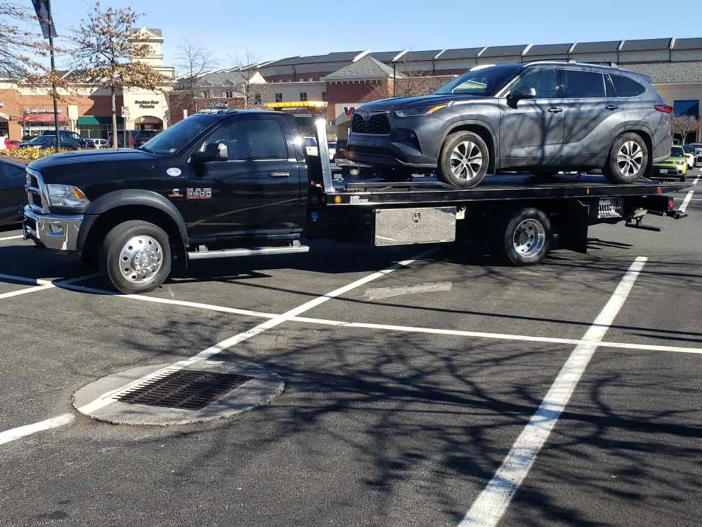 Black flatbed tow truck transporting Toyota Highlander SUV safely in Nashville