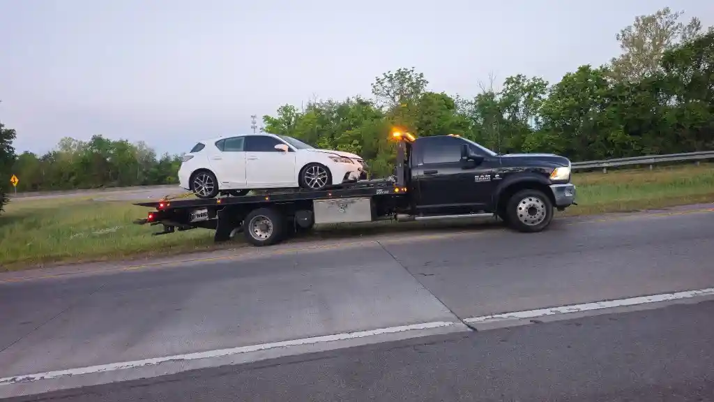 Hook Em' Up Towing flatbed loaded with a white Lexus on the I-65 shoulder near Nashville