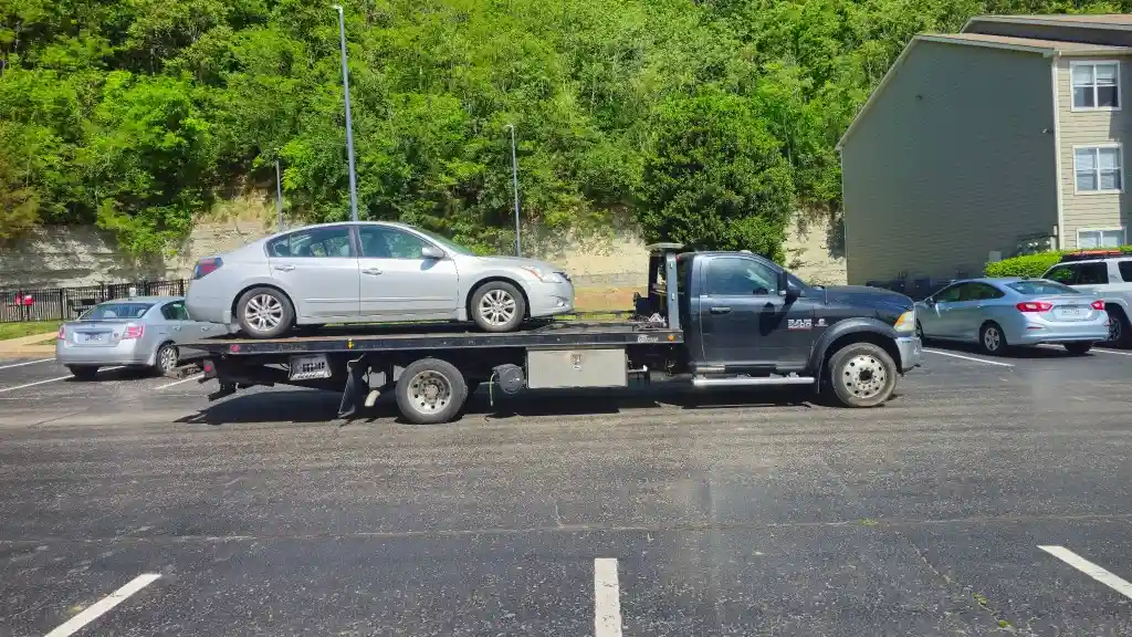 Hook Em' Up Towing flatbed loading a Tesla Model 3 on a Nashville street at night
