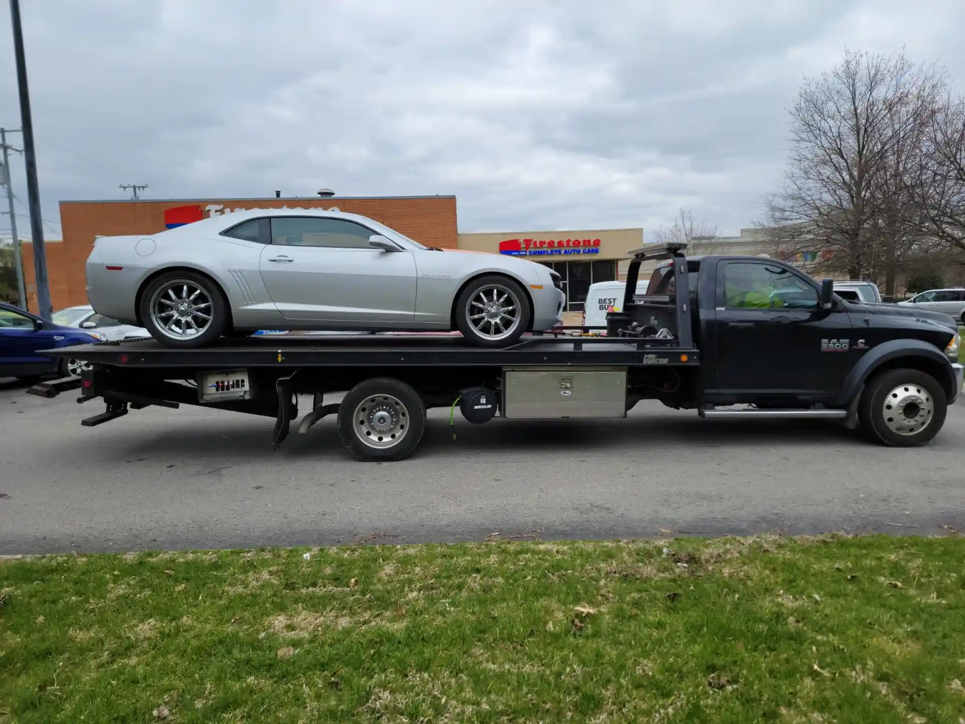 Silver Camaro on professional flatbed tow truck - comparing roadside assistance vs towing service Nashville