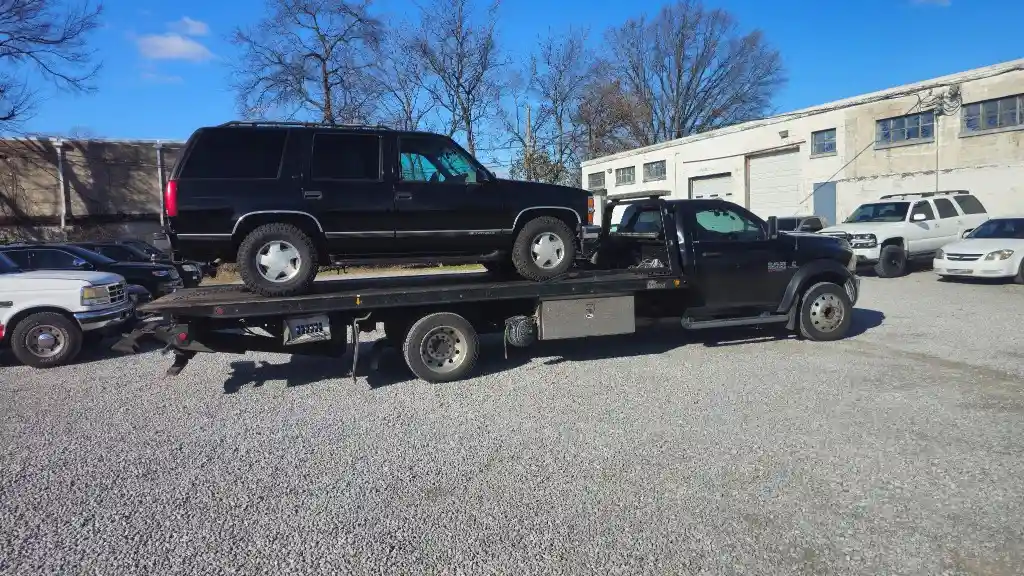 Black Chevrolet Tahoe 4WD secured on a Hook Em' Up Towing flatbed with all four wheels off the ground in Nashville