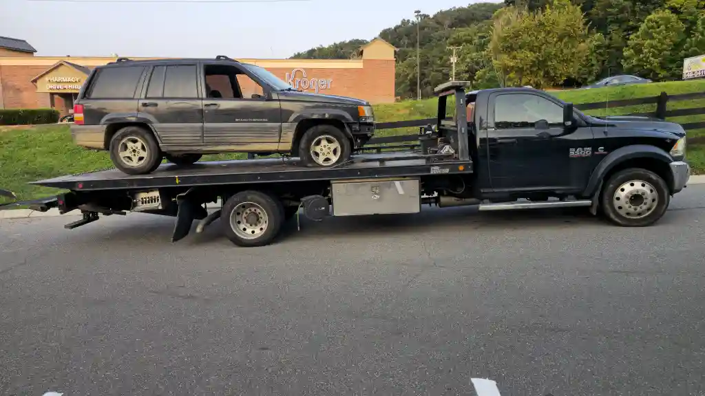 Jeep Grand Cherokee strapped onto a Hook Em' Up Towing flatbed outside a Nashville Kroger